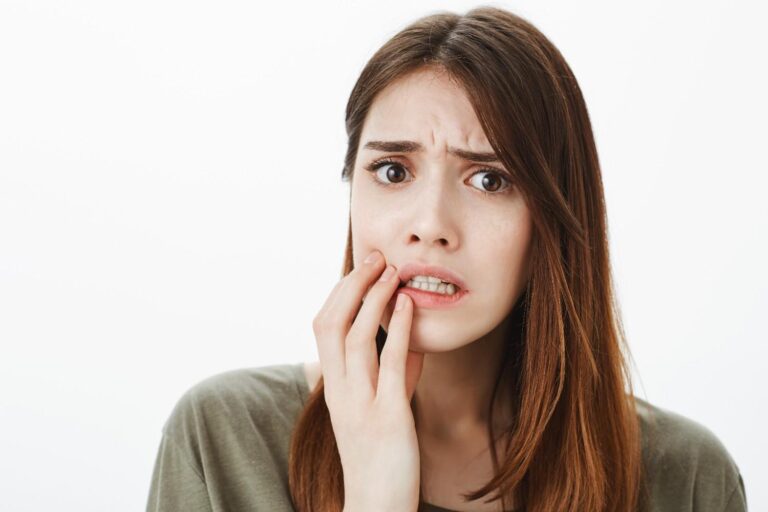 Person with a small cut on the gums showing redness and mild bleeding while examining the mouth in a mirror