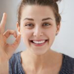 Person flossing teeth to remove plaque and maintain healthy gums