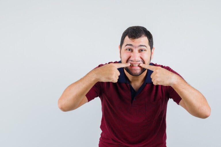 Man pointing at his gums to demonstrate the early signs of receding gums and gum recession.