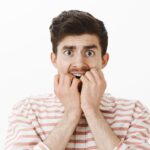 Adult with a loose tooth experiencing pain while holding their jaw, illustrating common causes and treatment options.