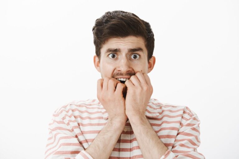 Adult with a loose tooth experiencing pain while holding their jaw, illustrating common causes and treatment options.