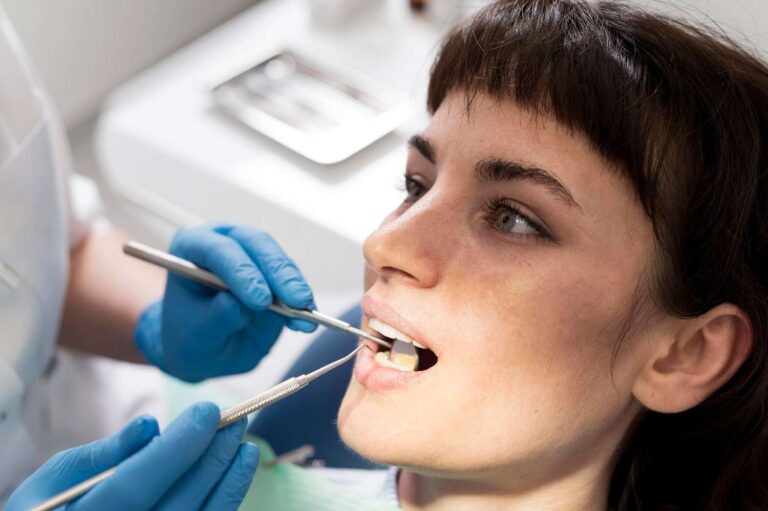 Dentist examining a patient's gums before an oral biopsy procedure to diagnose gum disease or abnormal mouth tissue.
