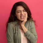Woman holding her cheek due to severe gum pain