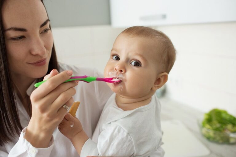Mother brushing baby teeth with a soft toothbrush during early oral care routine