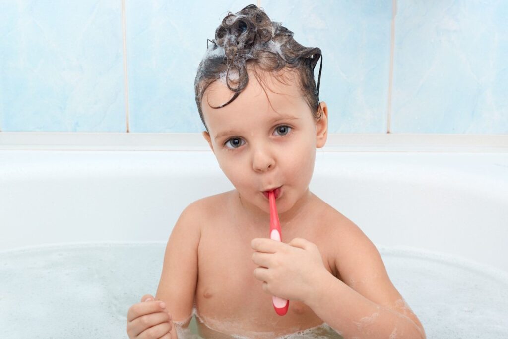 Toddler learning to brush teeth with a toothbrush as part of a daily oral hygiene routine