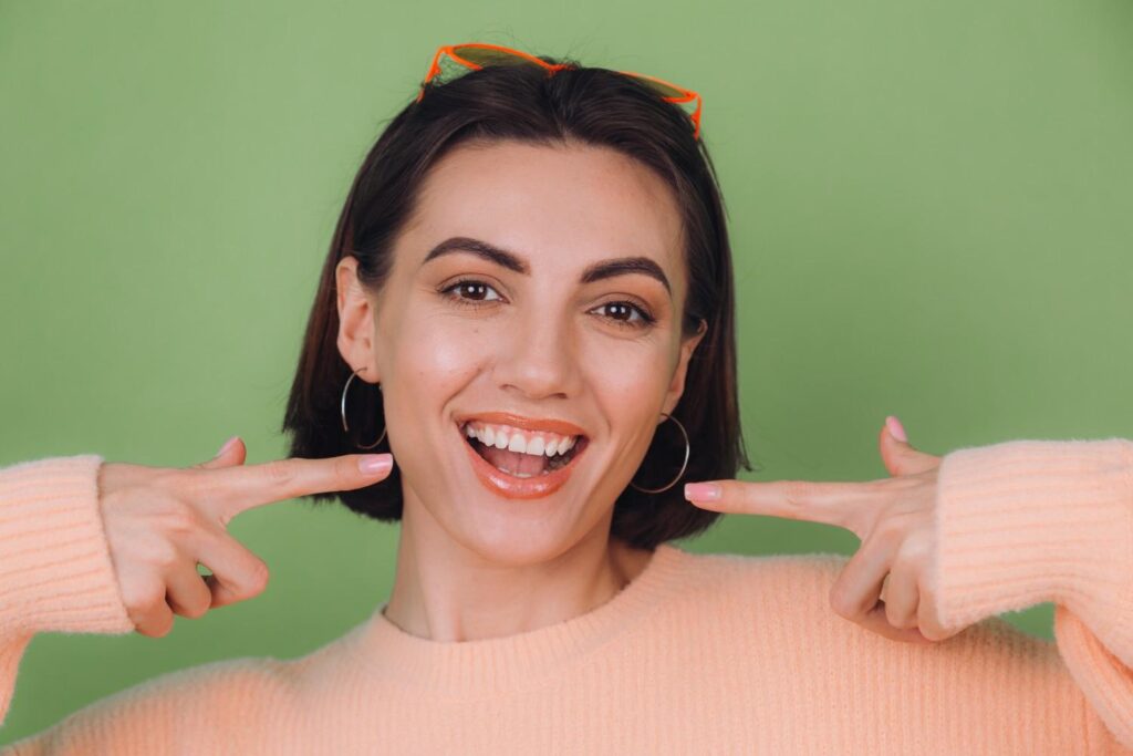 Woman pointing toward her smile, illustrating cosmetic treatment options for a gummy smile.